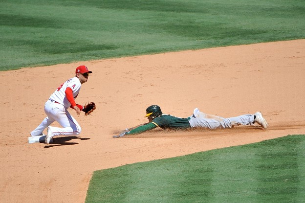 An Oakland Athletics player slides into second base to try and steal on the Los Angeles Angels.