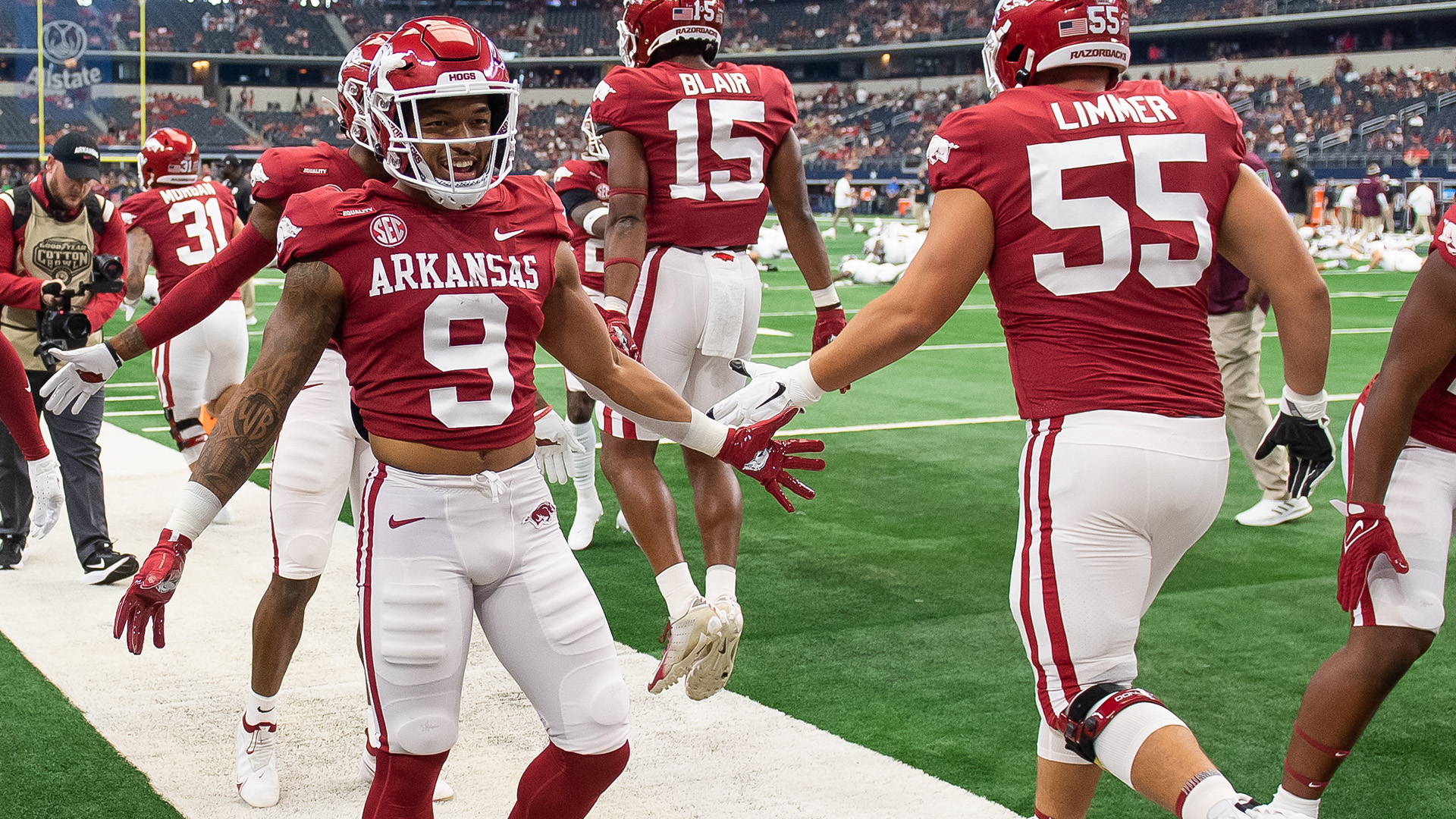 Arkansas college football players high five each other on the sidelines.