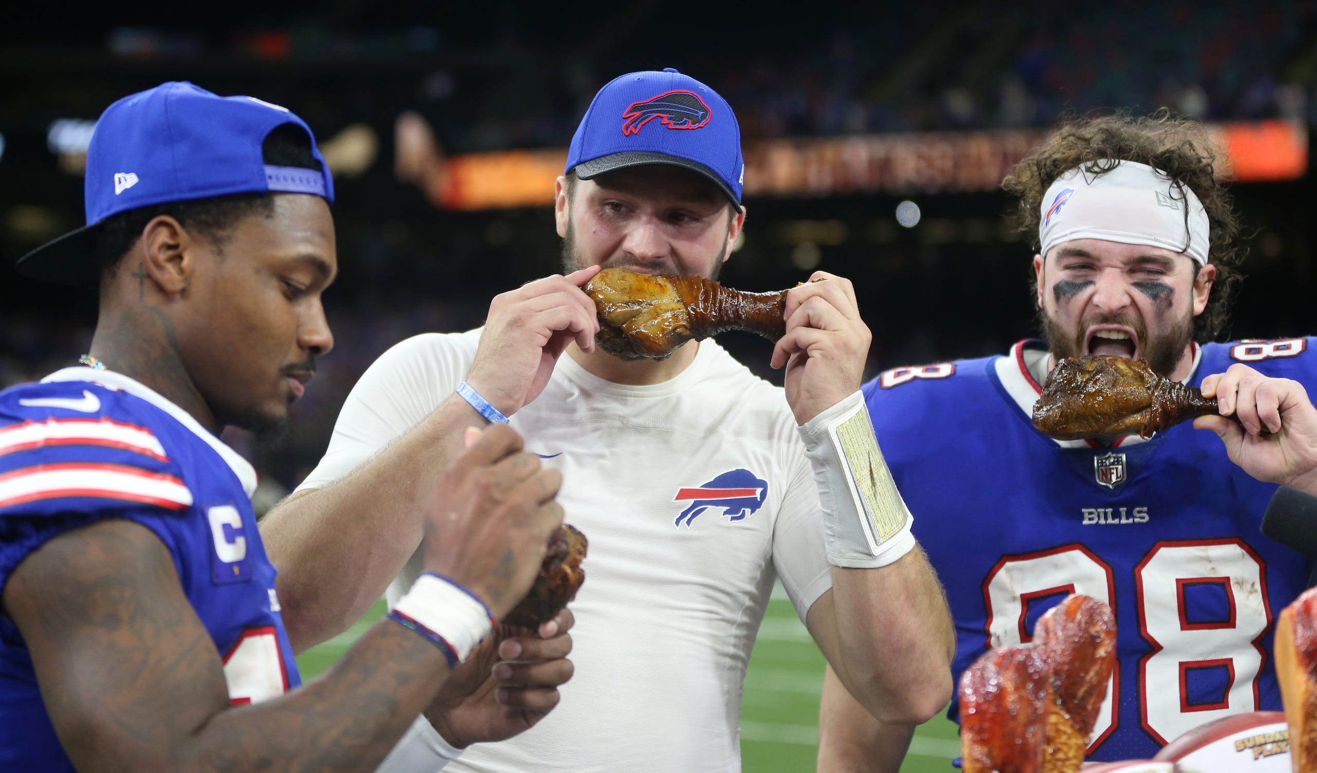 Three Buffalo Bills players eat turkey after a Thanksgiving game against the Saints.