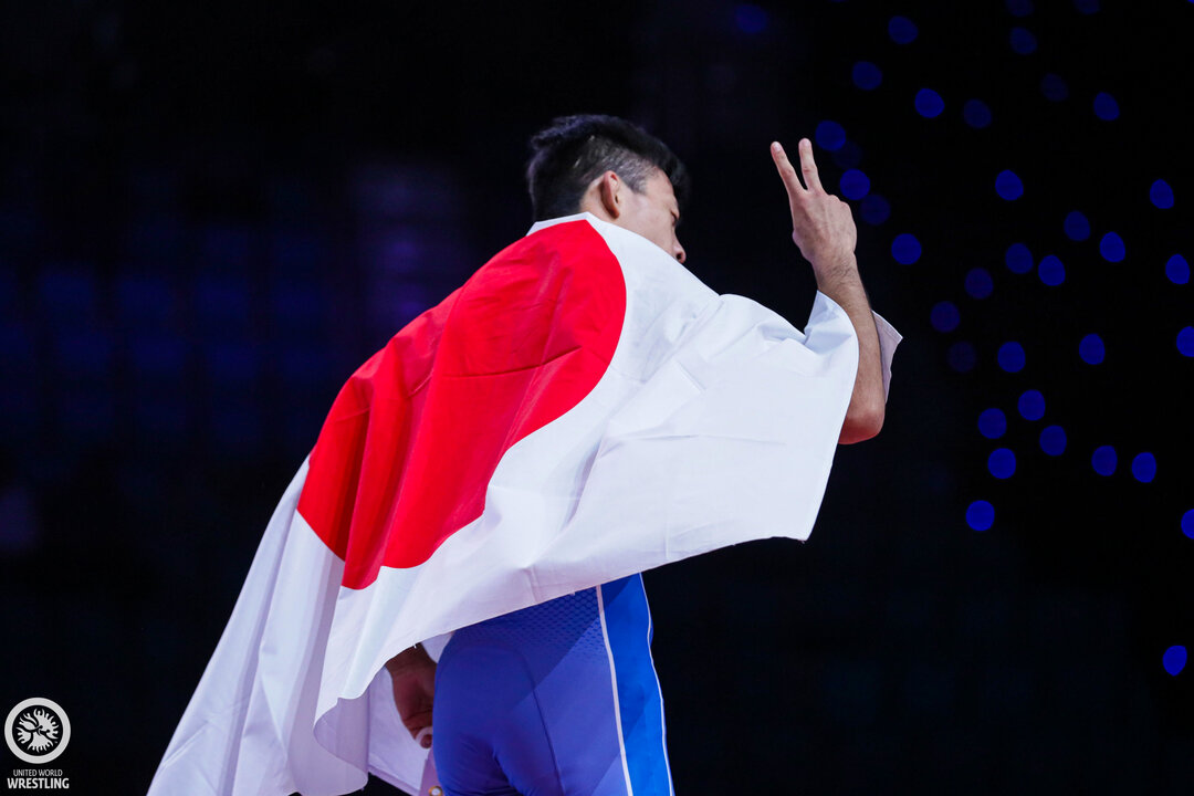 Japan's Fumita celebrates with a flag after a wrestling match.