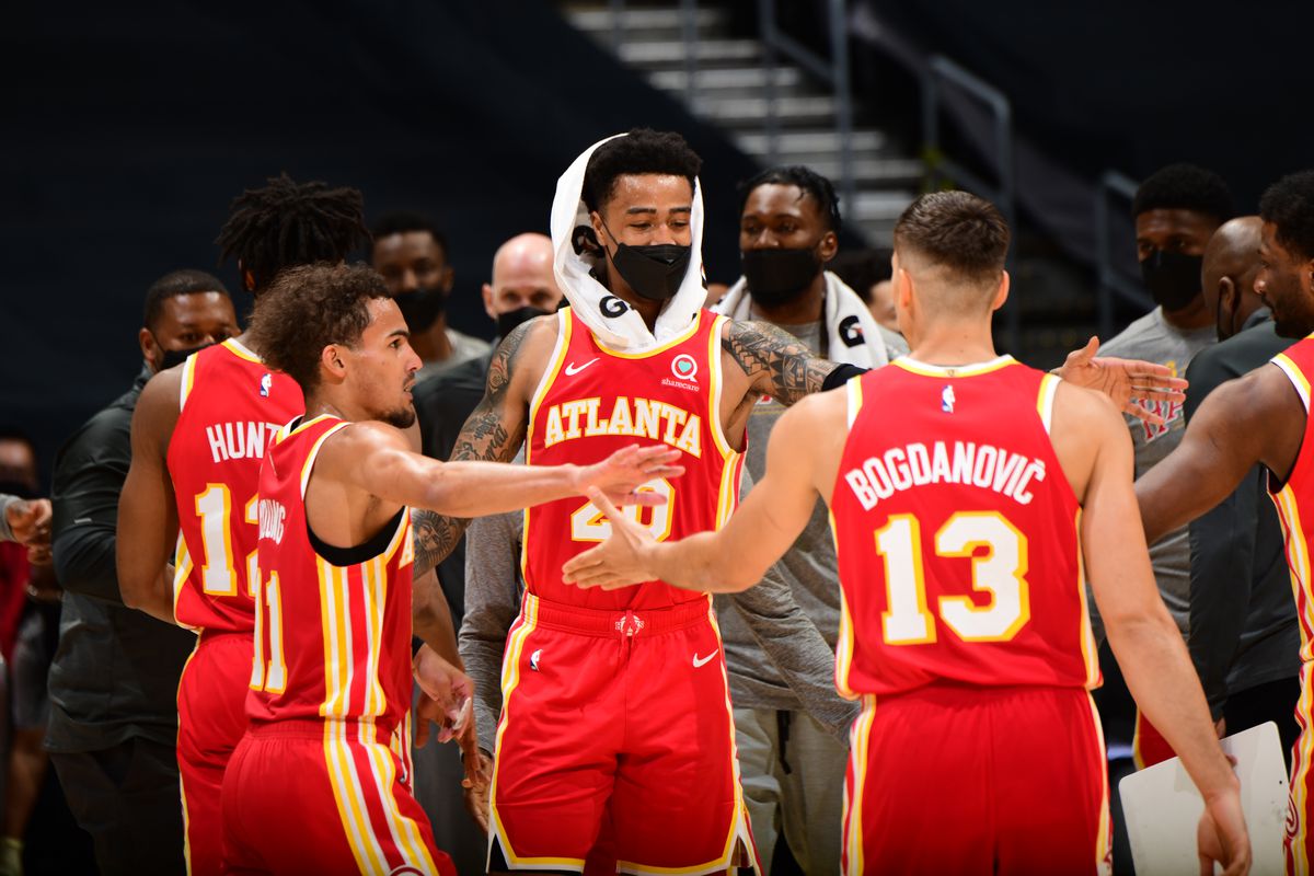 Three Atlanta Hawks players high-five during an NBA game.