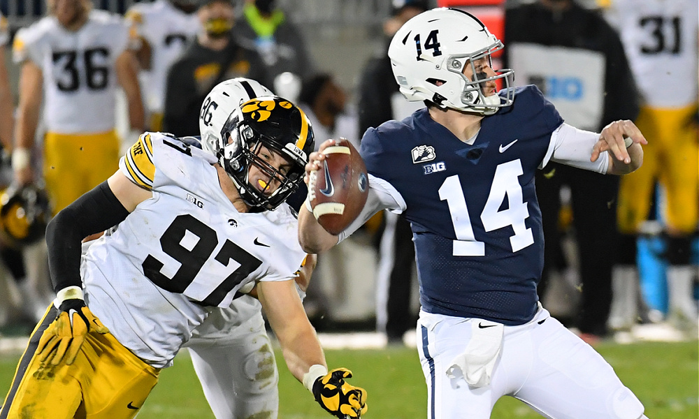 An Iowa defender attempts to sack a Penn State quarterback during a college football matchup.
