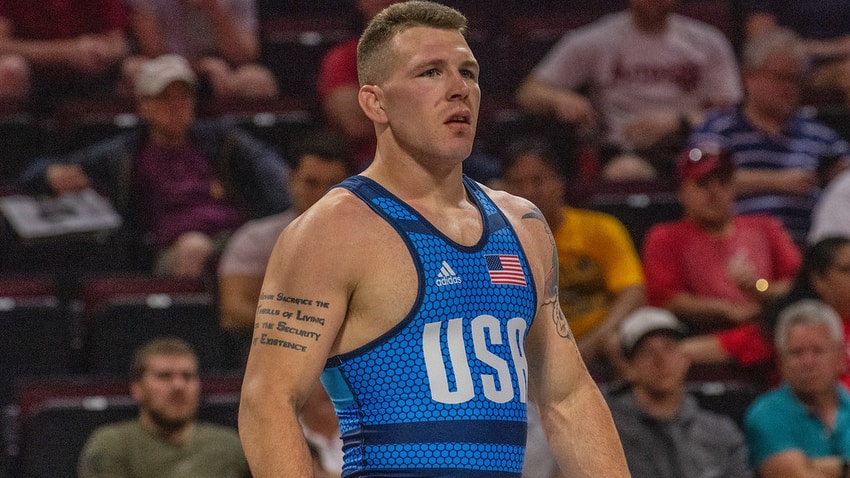 John Stefanowicz stands on a mat during a wrestling match.