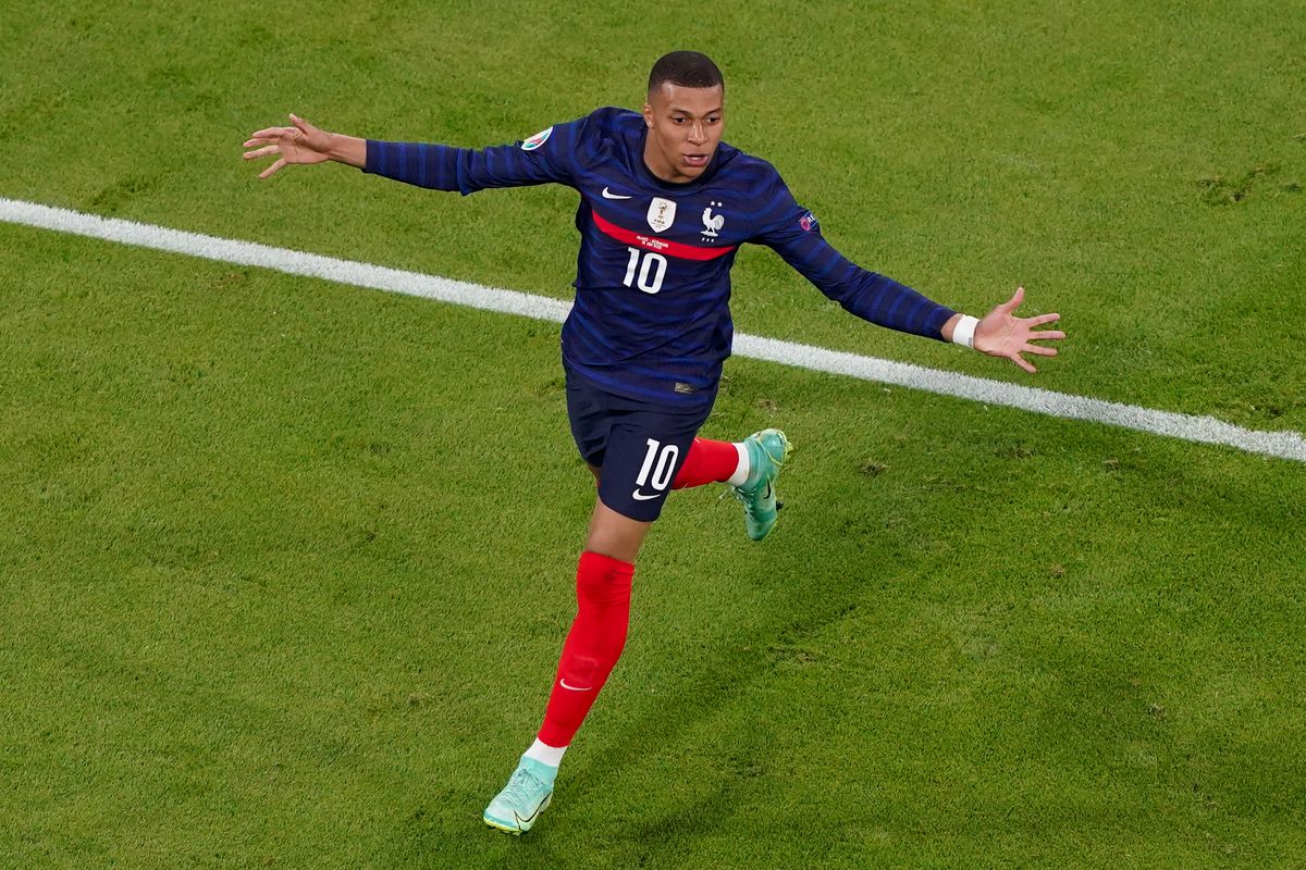 Kylian Mbappe celebrates with his arms out stretched during a soccer game.