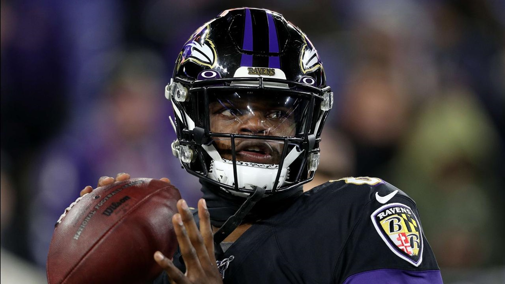 Baltimore's Lamar Jackson stands on the field with a football during a game.