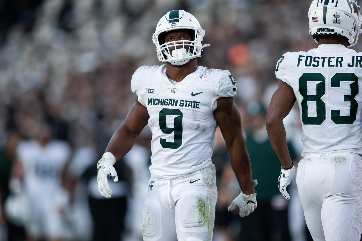 Two Michigan State players stand on the field during a college football game