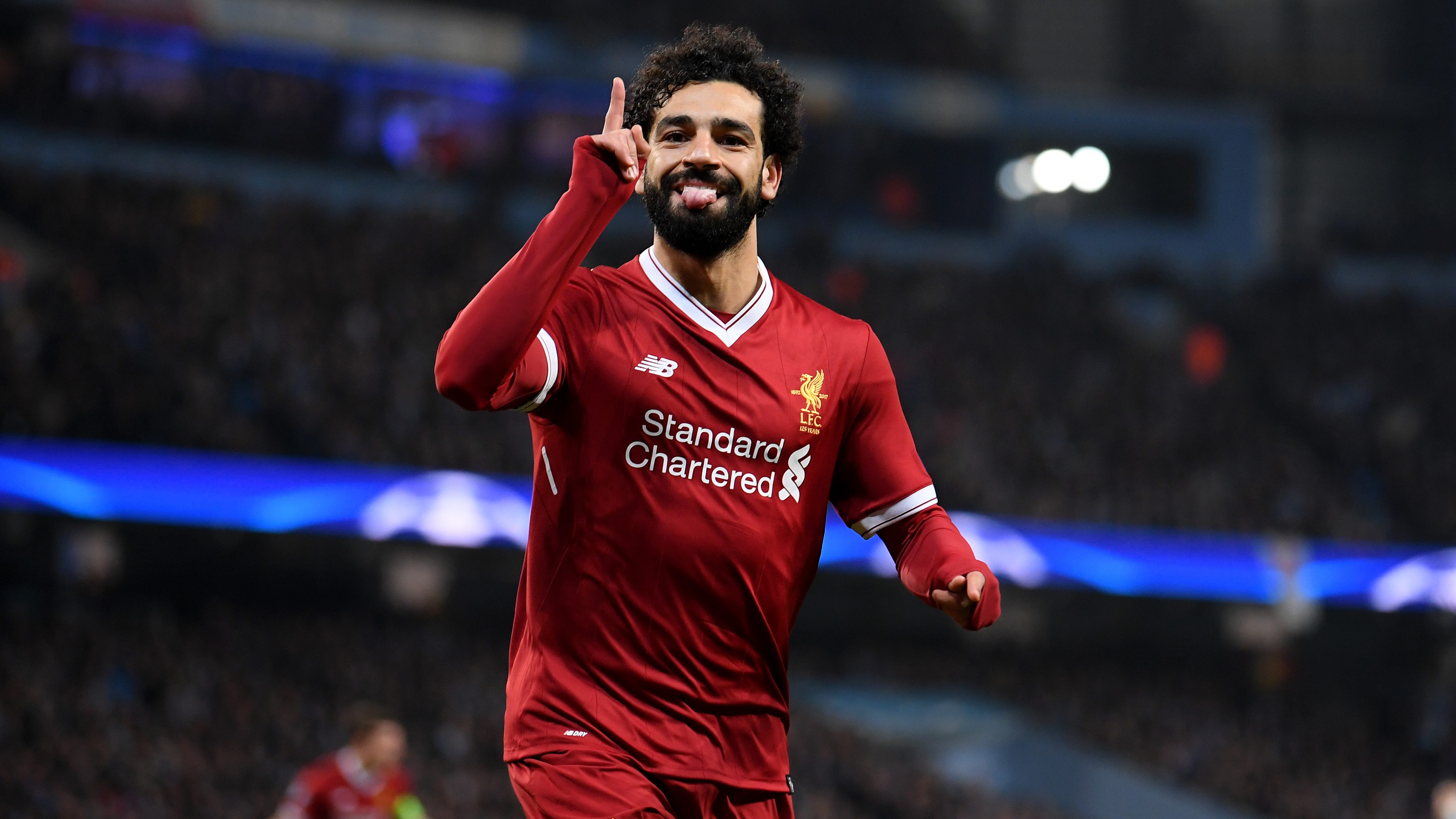 Mohamed Salah celebrates with a hand pointing towards the sky during a soccer game.