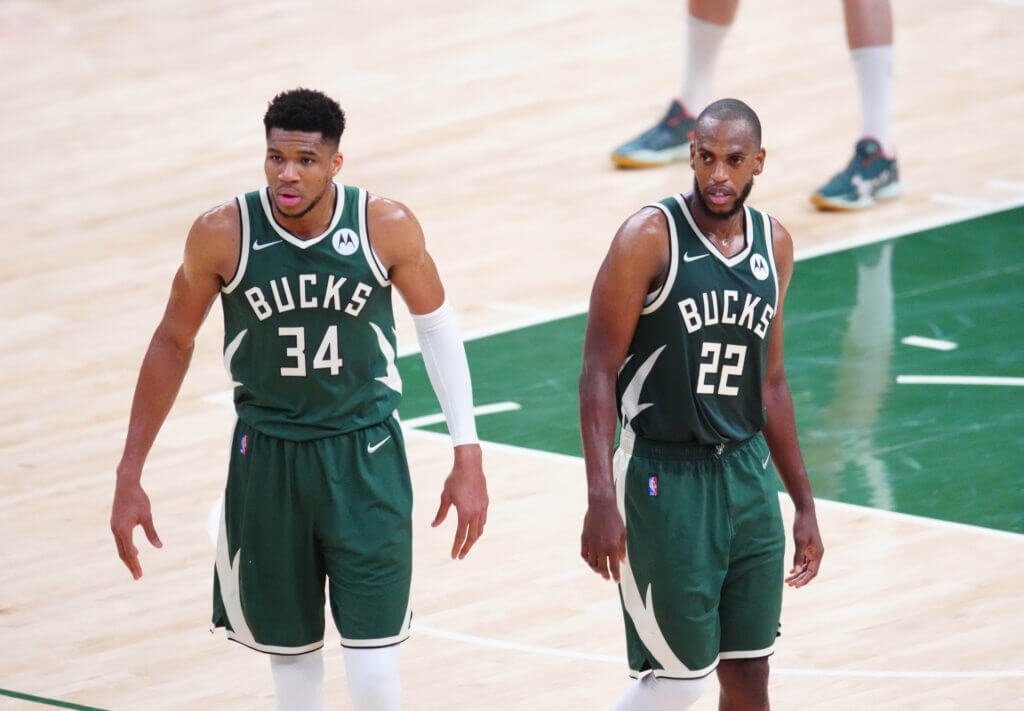 Two Milwaukee Bucks players stand on the court during a game.