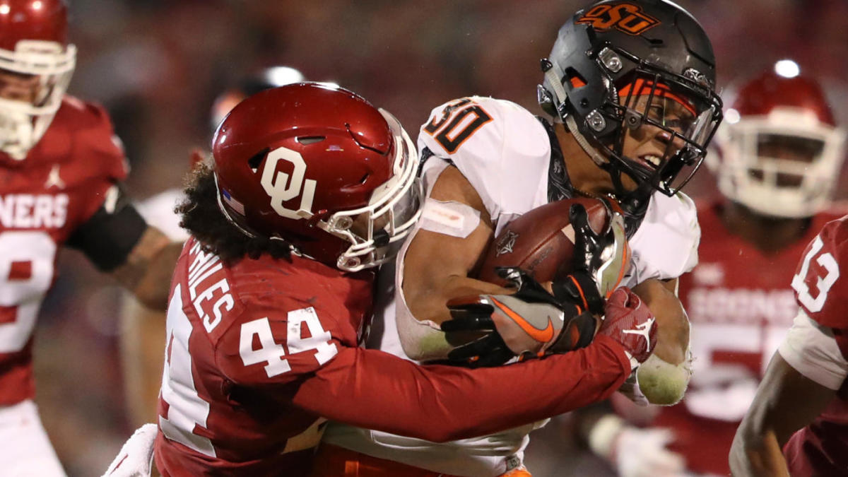 An Oklahoma player tackles an Oklahoma State player during a college football game.