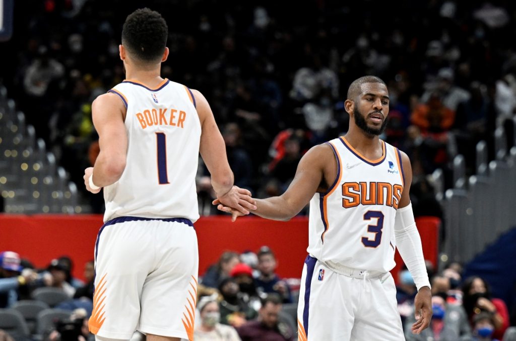 Phoenix's Devin Booker and Chris Paul high five during an NBA game.