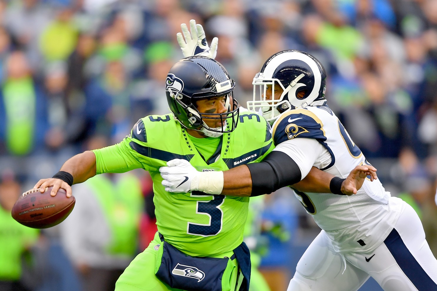Seattle's Russell Wilson avoids LA Rams defenders during a NFL game.