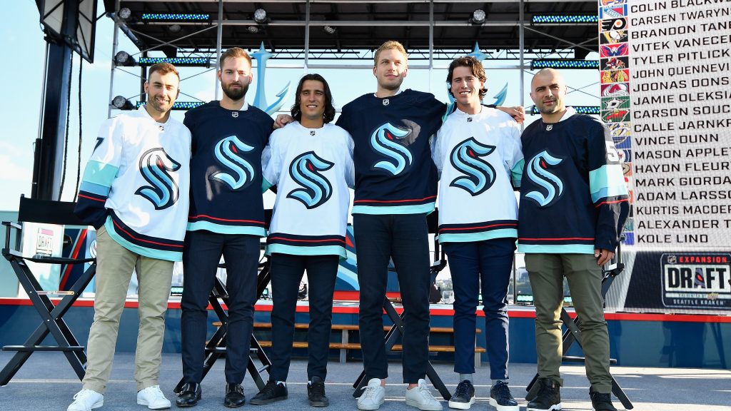 The new members of the Seattle Kraken roster stand on the stage during the 2021 Expansion Draft.