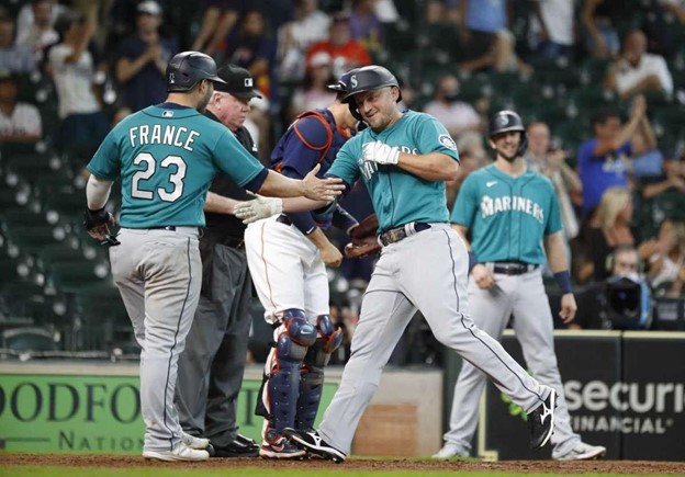 Seattle Mariners players celebrate at home plate during a MLB game.