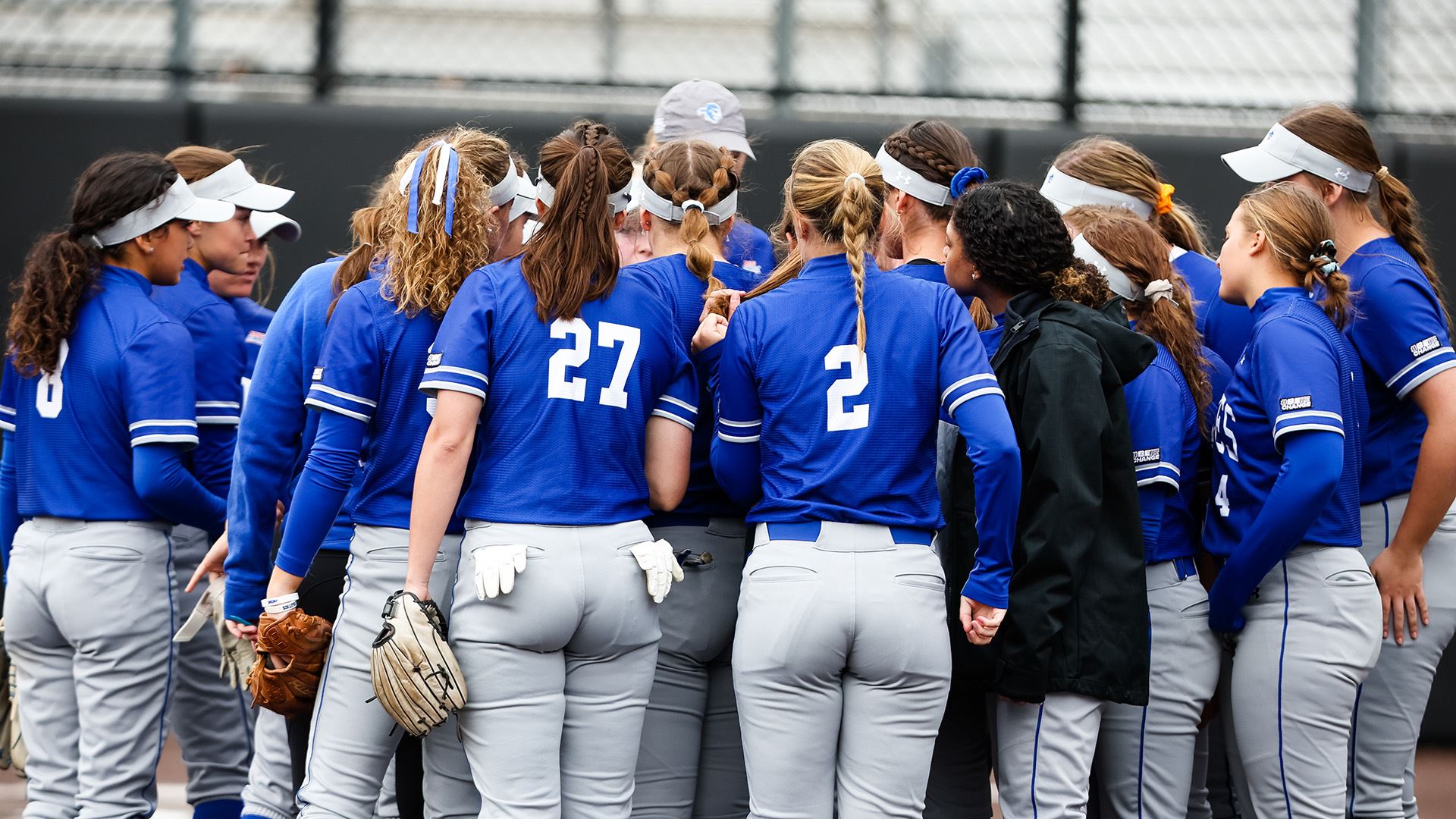 The Seton Hall softball team stands in a huddle during a game.