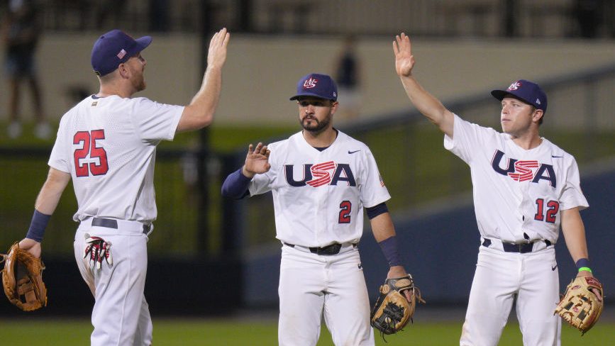 Three Team USA baseball teammates high-five during a game.