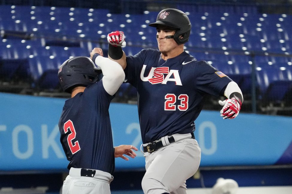 Two USA baseball players celebrate at home plate during an Olympics game.