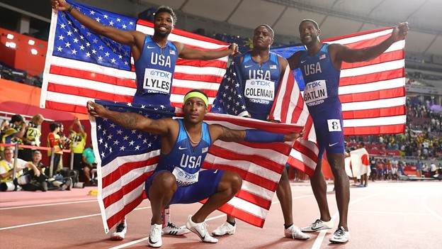 A relay team of USA sprinters celebrate after winning a track race.