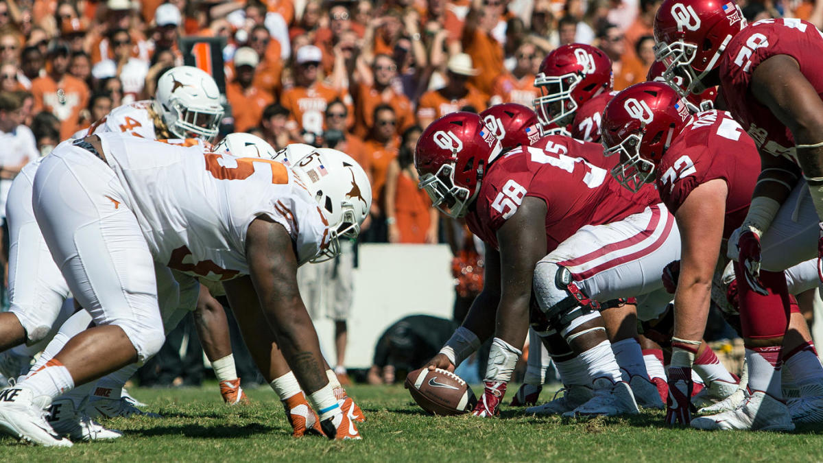 Texas and Oklahoma line up against each other at the line of scrimmage in college football.