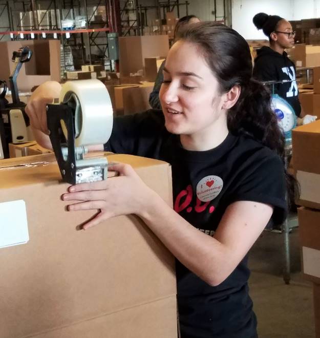 Promo Dirrector Tayla preps a cardboard box with tape