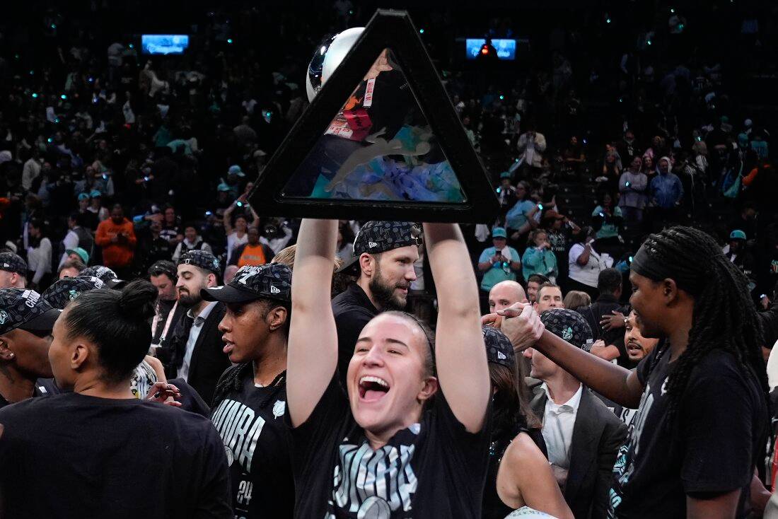 Liberty guard Sabrina Ionescu holds up the championship trophy after the Liberty defeated the Minnesota Lynx in Game 5 of the WNBA Finals.